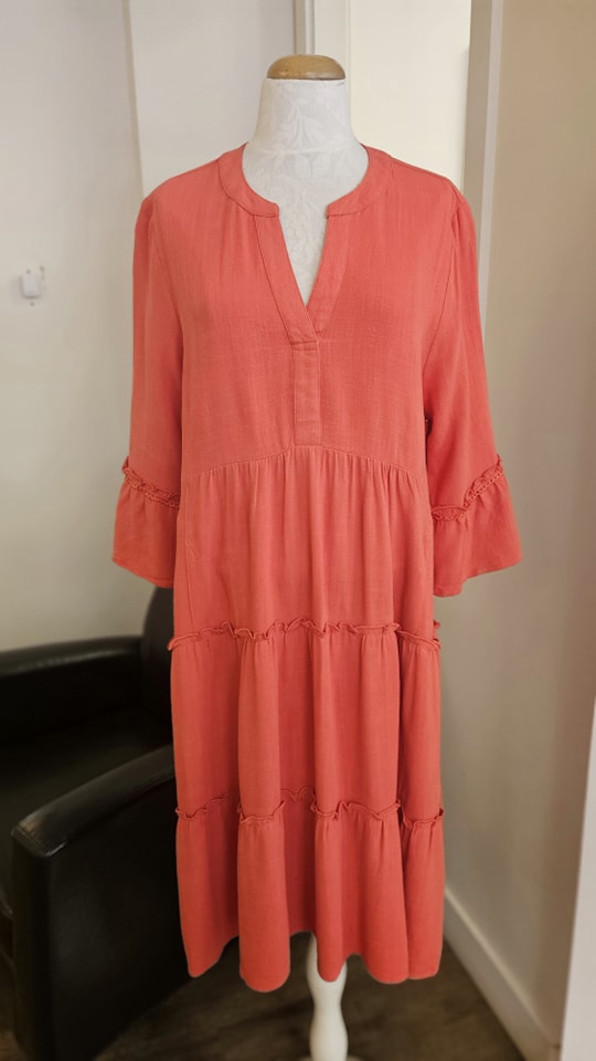 Coral tiered dress with v-neck and bell sleeves on a mannequin