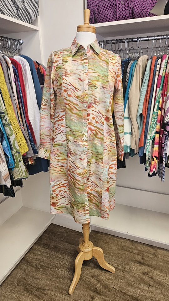 Colourful watercolour print shirt dress on a mannequin surrounded by racks of clothing inside Jorie's Fine Clothing