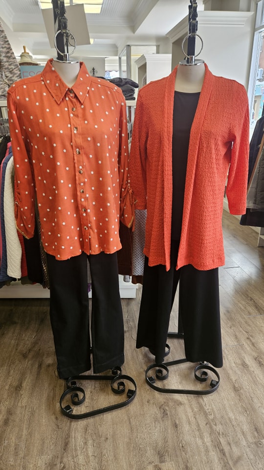 Polka dot blouse and open-front cardigan paired with black pants on display